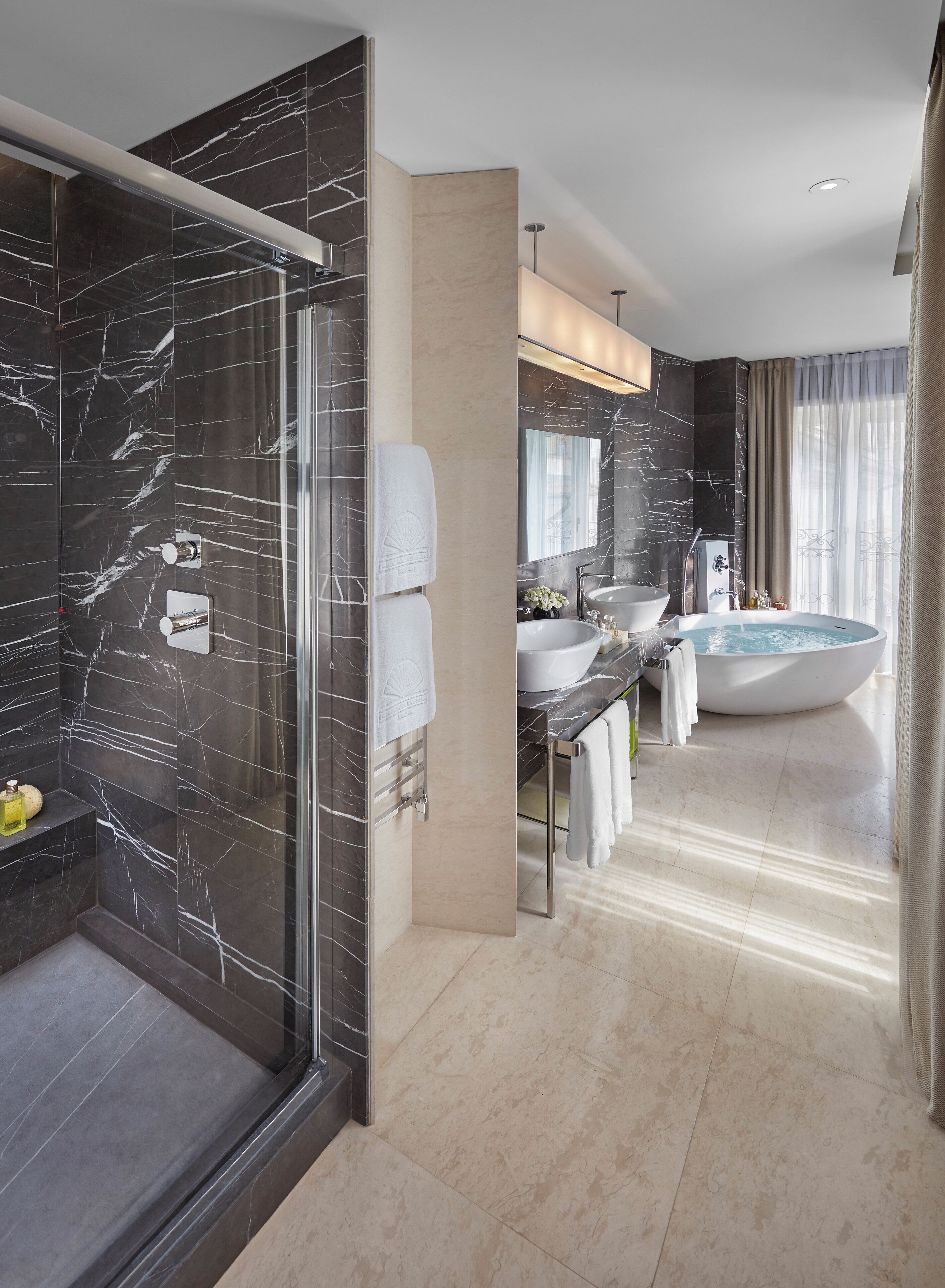 Ein modernes Badezimmer mit einer gläsernen Duschkabine, einer großzügigen Badewanne und einem Waschtisch mit Spüle und Spiegel.