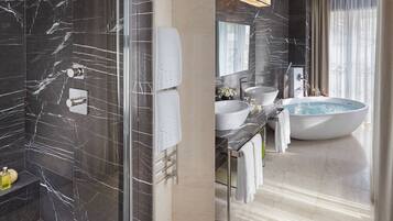 Ein modernes Badezimmer mit einer gläsernen Duschkabine, einer großzügigen Badewanne und einem Waschtisch mit Spüle und Spiegel.