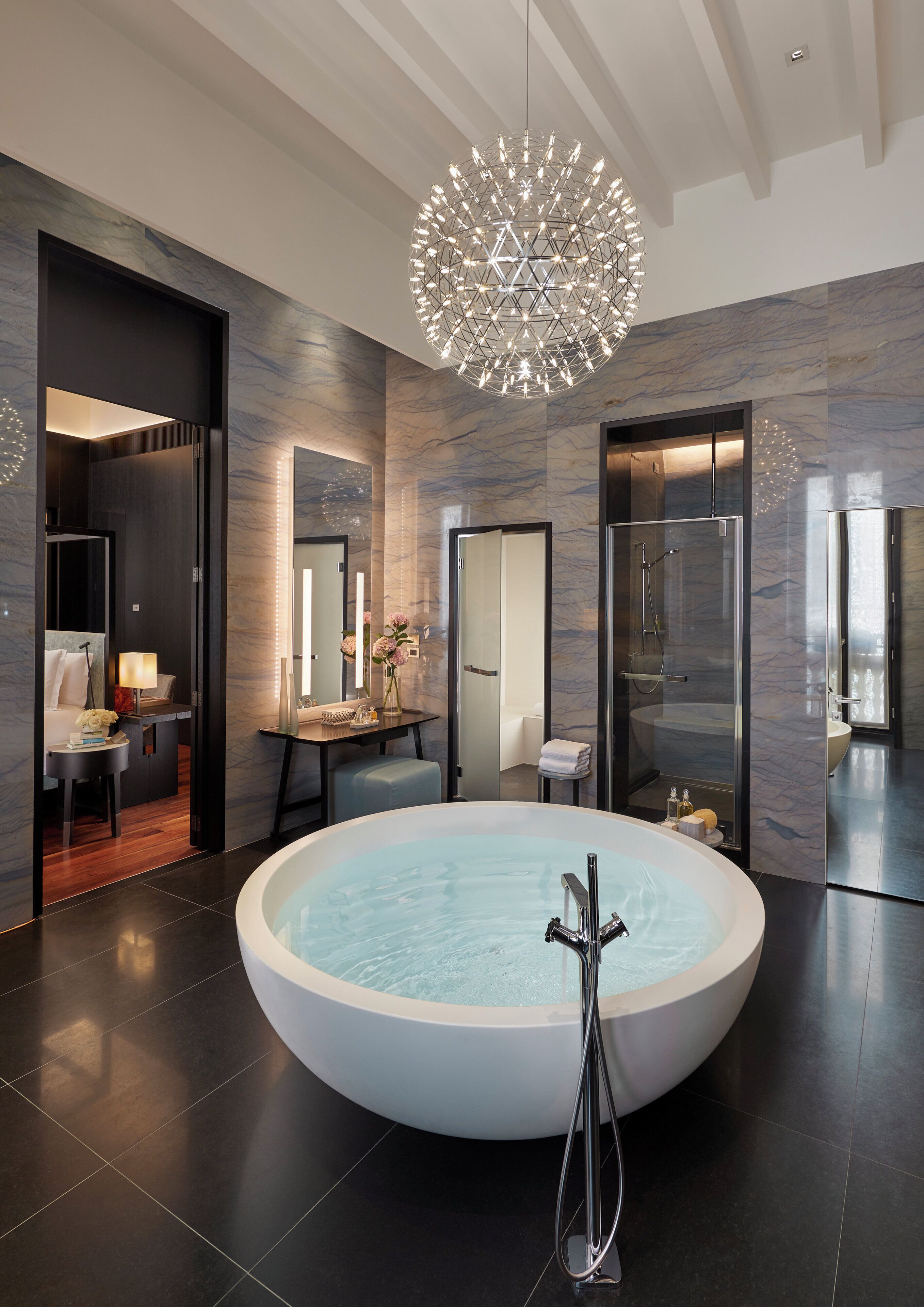 Ein modernes Badezimmer mit einer großzügigen, freistehenden Badewanne, einer gläsernen Dusche und einem dekorativen Kronleuchter.