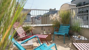 A rooftop terrace with a wooden table, two blue chairs, and a potted plant. - Ruby Sofie Hotel Vienna by IHG (Vienna)