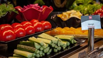 Una barra de ensaladas con diversas verduras frescas, incluyendo tomates, pepinos y otras hojas verdes.