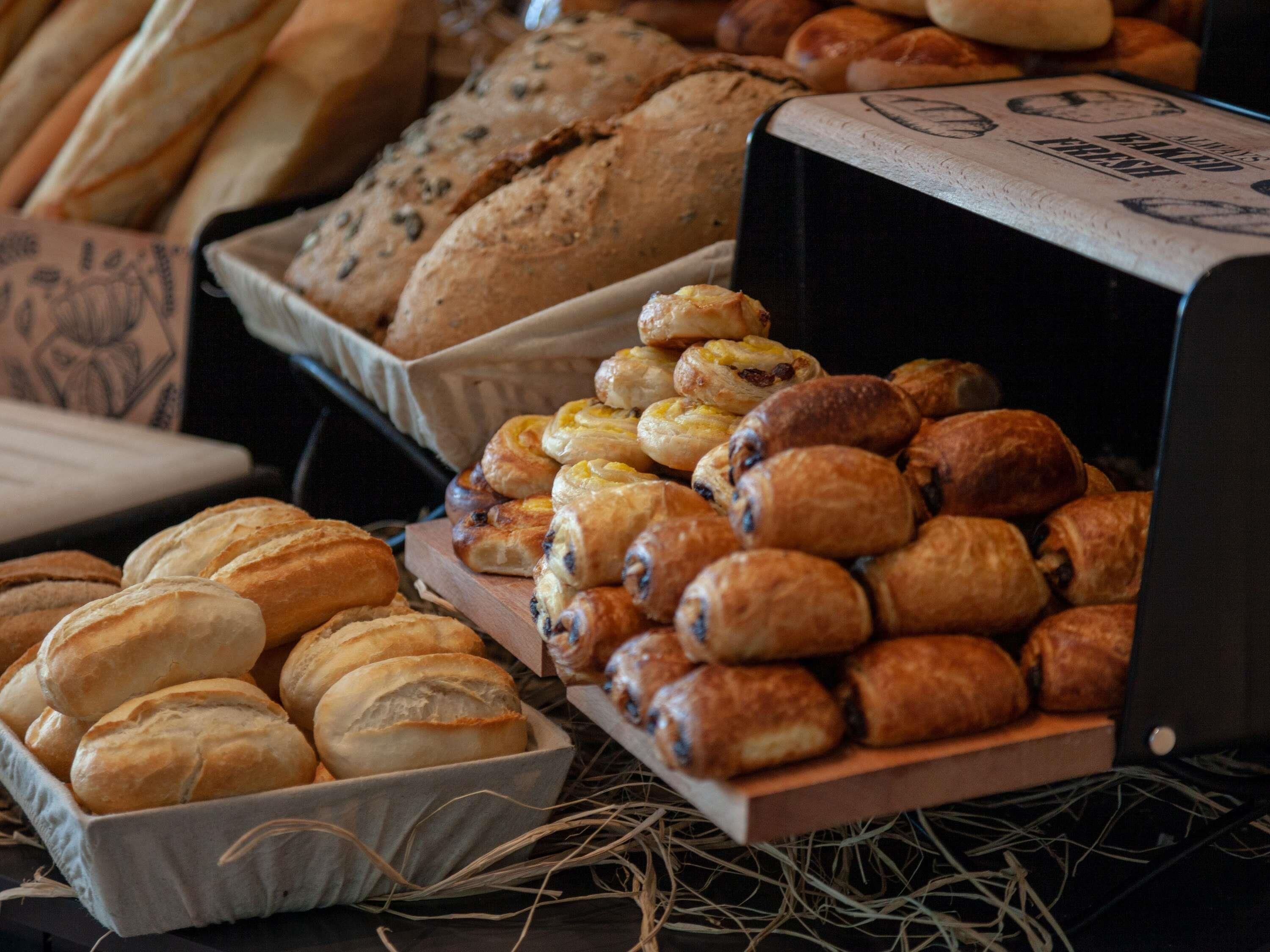 A variety of baked goods including bread, rolls, and pastries displayed in trays and boxes.