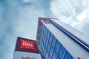 Un edificio de hotel alto con un cartel llamativo de 'ibis Hotels' en la parte superior.