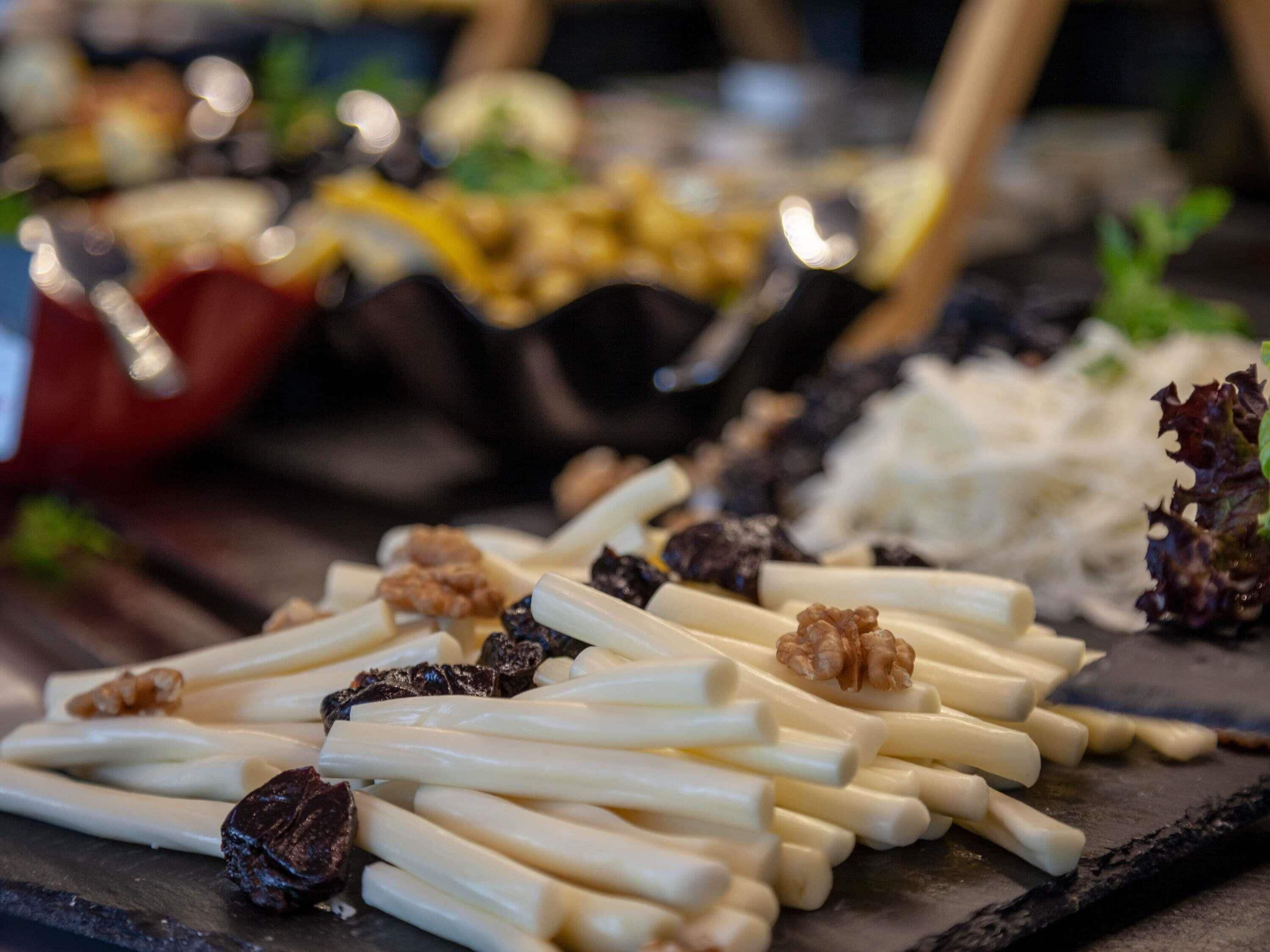 A variety of cheeses and nuts on a slate board.
