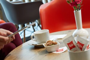 A table with a cup, a bowl of food, and a vase with flowers.