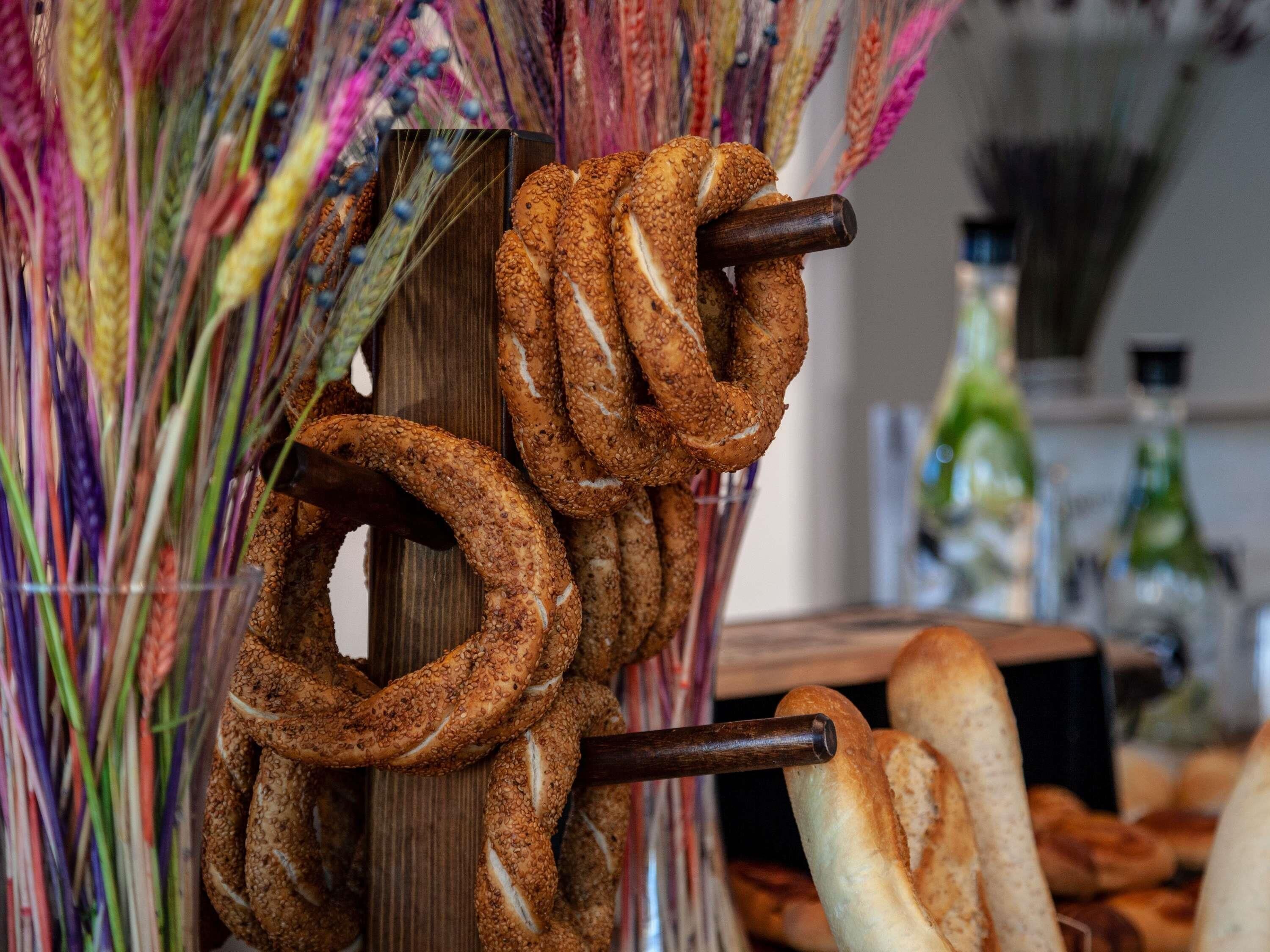 Pretzels colgados en un soporte, con un fondo de madera y una botella al fondo.