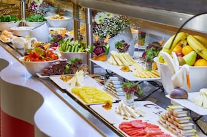 A buffet with various food items including fruits, vegetables, and cheeses.
