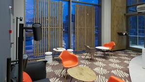 A modern interior with a large window, wooden slats, orange chairs, and a chessboard. - Ibis Konya (Konya)