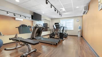 Un gimnasio con cintas de correr, elípticas y una prensa de banca.