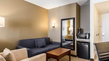 A hotel room with a sofa, a small table, a microwave, and a coffee maker.