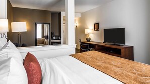 A hotel room with a bed, a desk, a television, a mirror, and a coffee machine. - Comfort Suites Woodland - Sacramento Airport (Woodland)