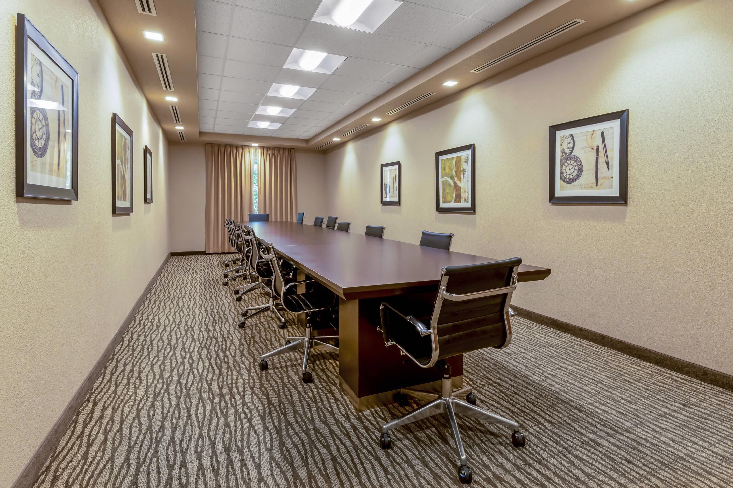 A conference room with a long table, chairs, and framed artwork on the walls.