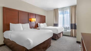 A hotel room with two beds, a nightstand, a lamp, and a window with curtains.