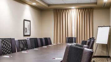 A conference room with a long table, chairs, a whiteboard, and a framed picture on the wall.
