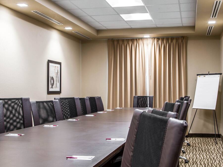 A conference room with a long table, chairs, a whiteboard, and a framed picture on the wall.