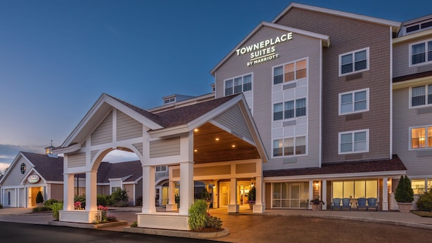 A Towneplace Suites hotel with a covered entrance, multiple floors, and a well-lit facade. - TownePlace Suites by Marriott Wareham Buzzards Bay (Wareham)