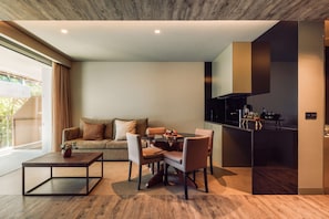 A modern living space with a dining area, a sofa, and a kitchen.