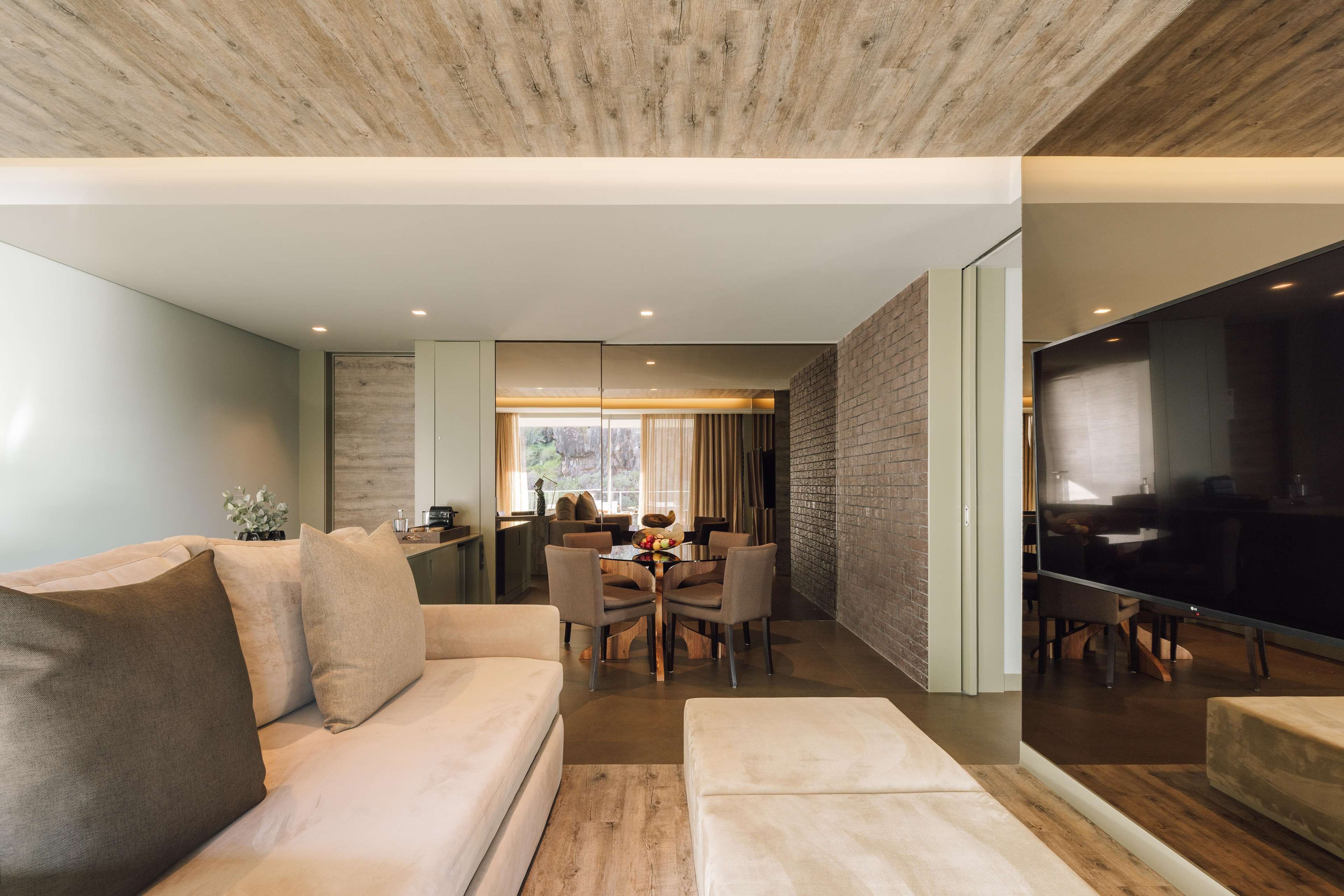 A modern living room with a sofa, ottoman, and a dining area with a table and chairs.