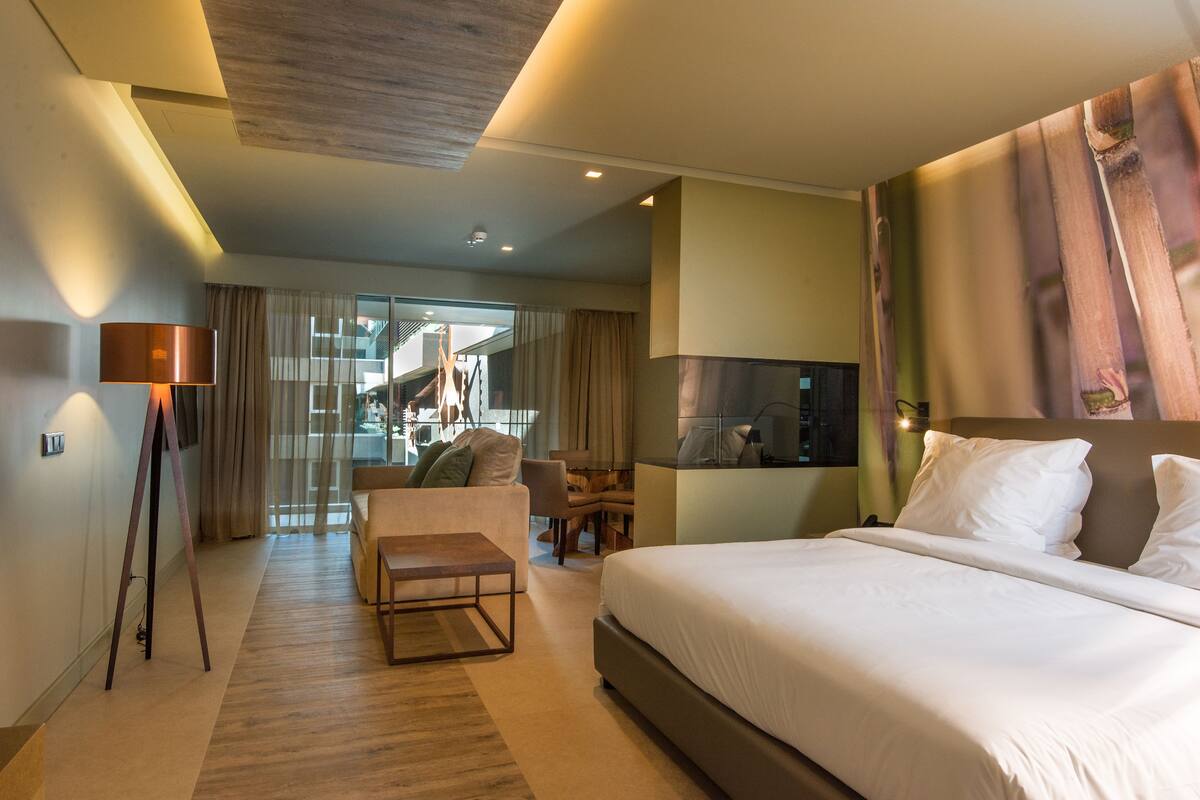 A modern hotel room with a large bed, a desk, and a seating area.
