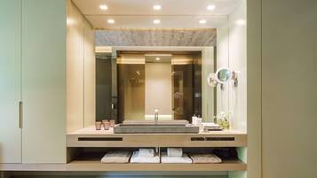 A modern bathroom with a large mirror, a sink, and built-in shelves for towels.