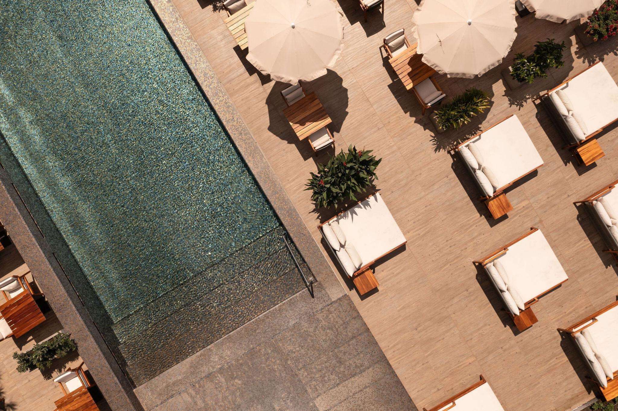 An aerial view of a poolside area with lounge chairs and umbrellas.