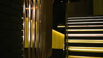 A staircase with illuminated handrails and a wooden slatted structure on the left.