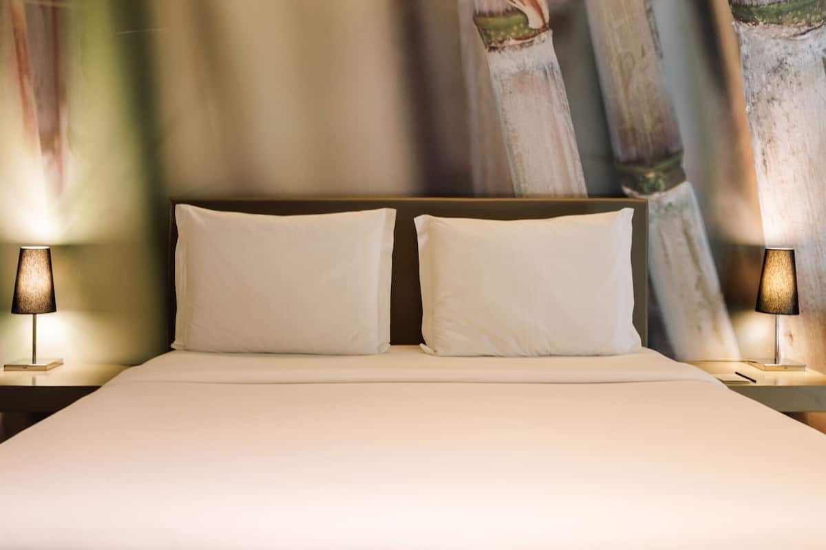 A bed with two pillows and two bedside lamps in a hotel room.