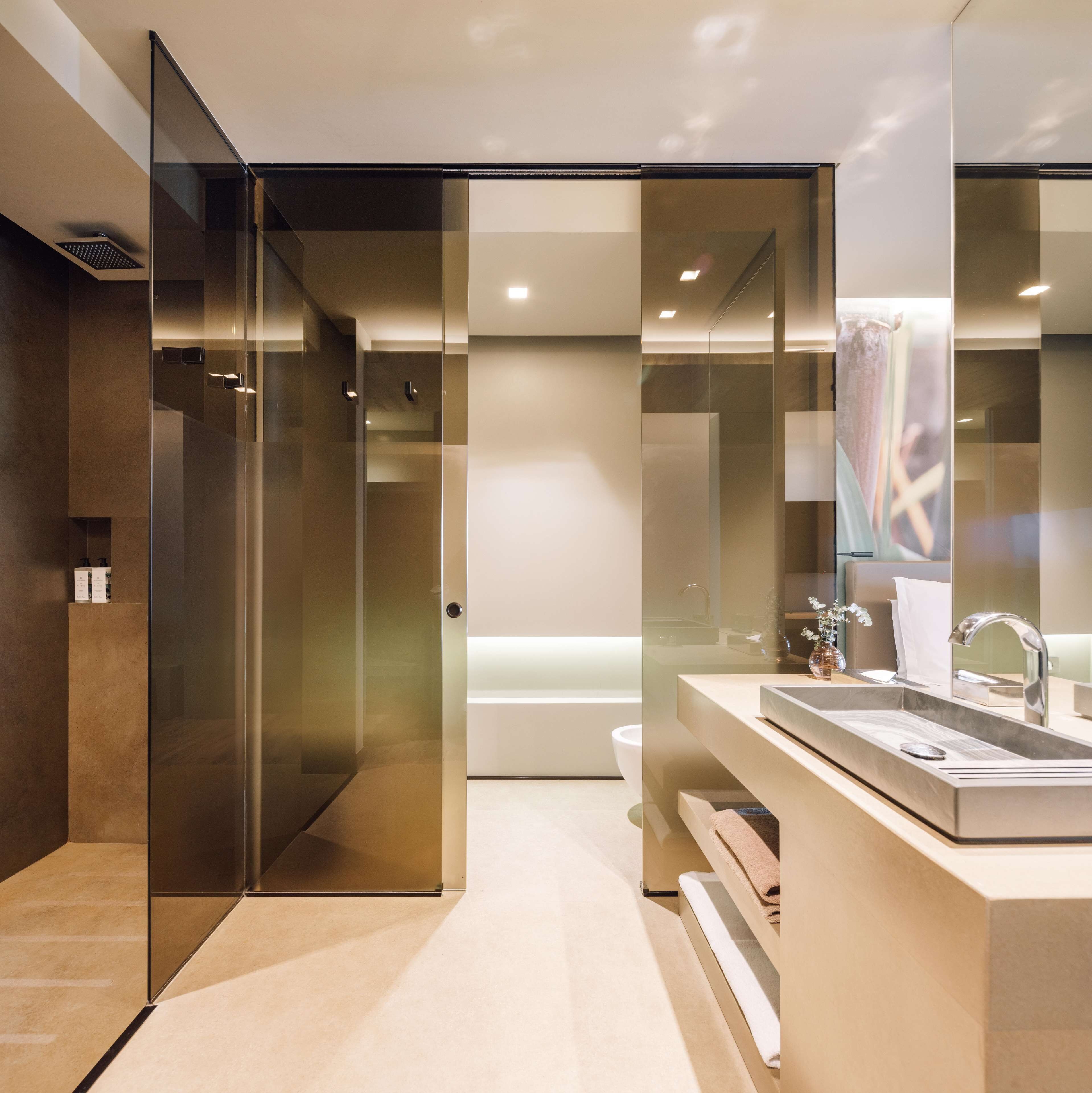 A modern bathroom with a glass shower enclosure, a large mirror, and a sink with a towel rack.
