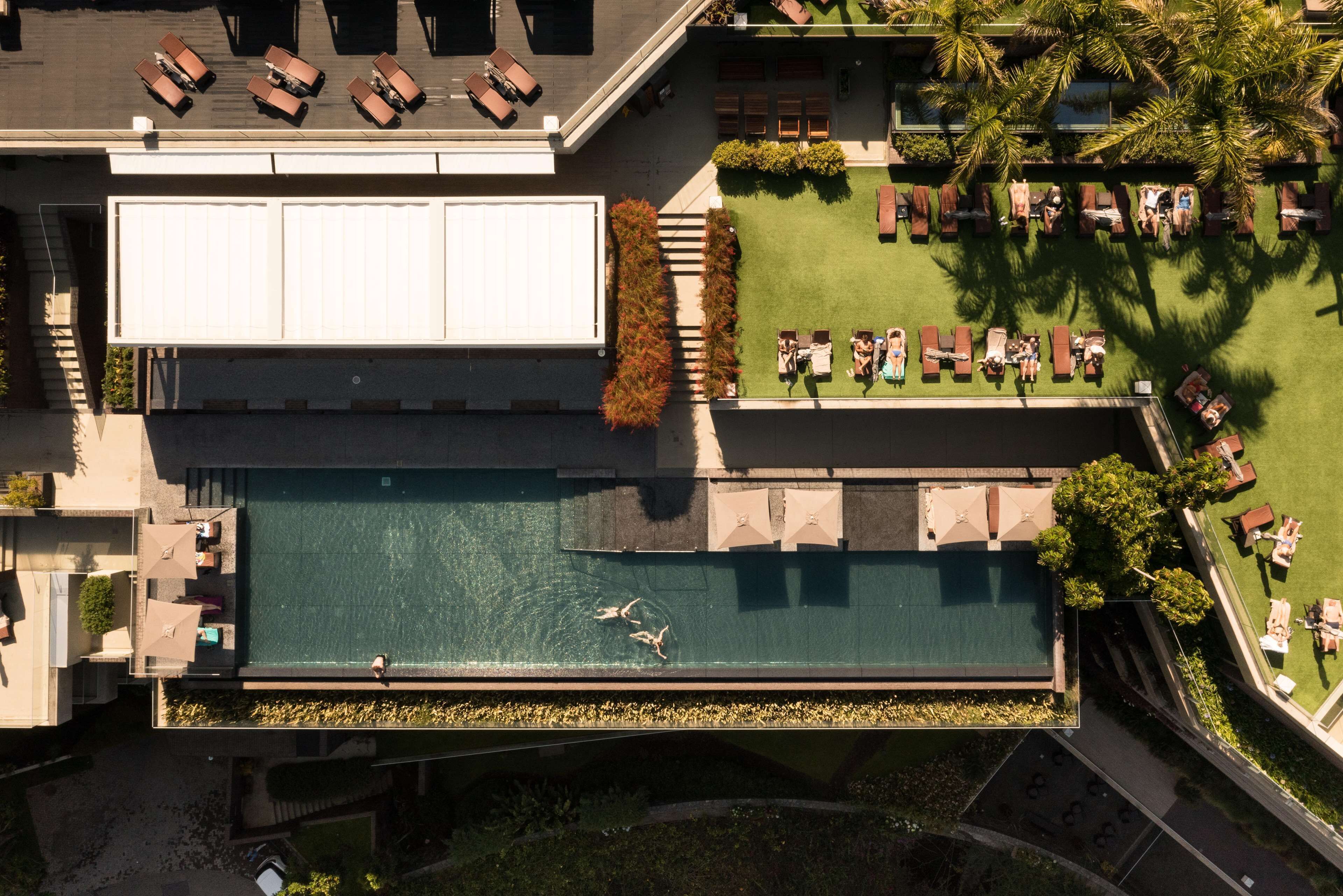 Vue aérienne d’un hôtel doté d’une piscine, d’espaces de détente et d’une terrasse couverte.