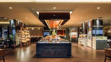 Eine moderne Hotellobby mit einem zentralen Buffet, Sitzbereichen und einer Treppe zu den oberen Etagen.
