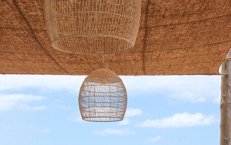 A wooden outdoor seating area with a table set for two, overlooking a calm sea.