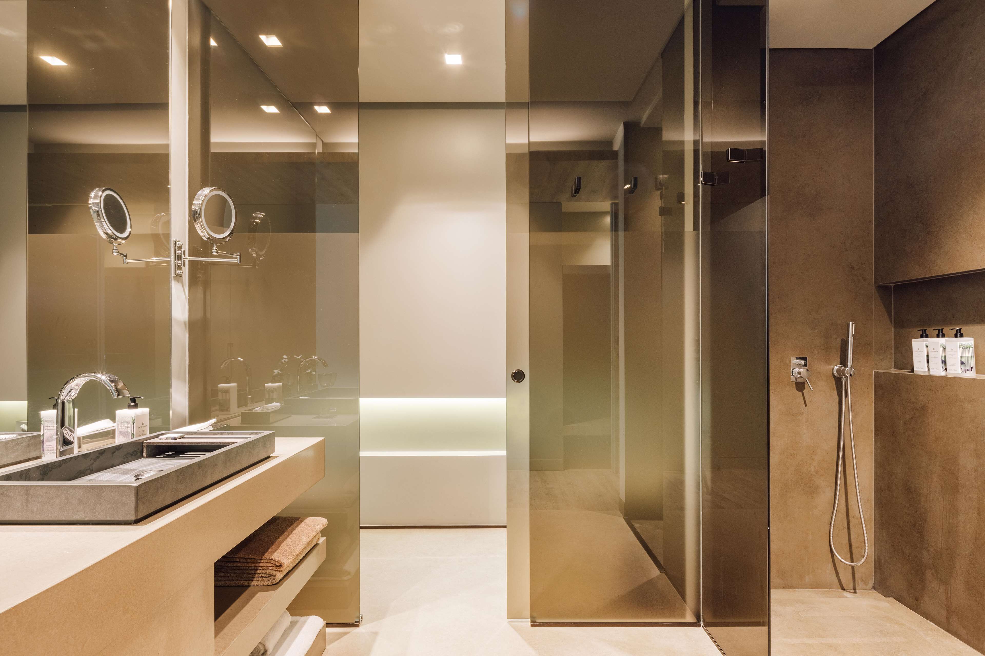 Un baño moderno con ducha de vidrio, tocador con lavabo y espejo.