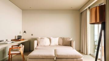 Quarto moderno com uma grande sofá-cama, uma escrivaninha com abajur e uma cadeira.