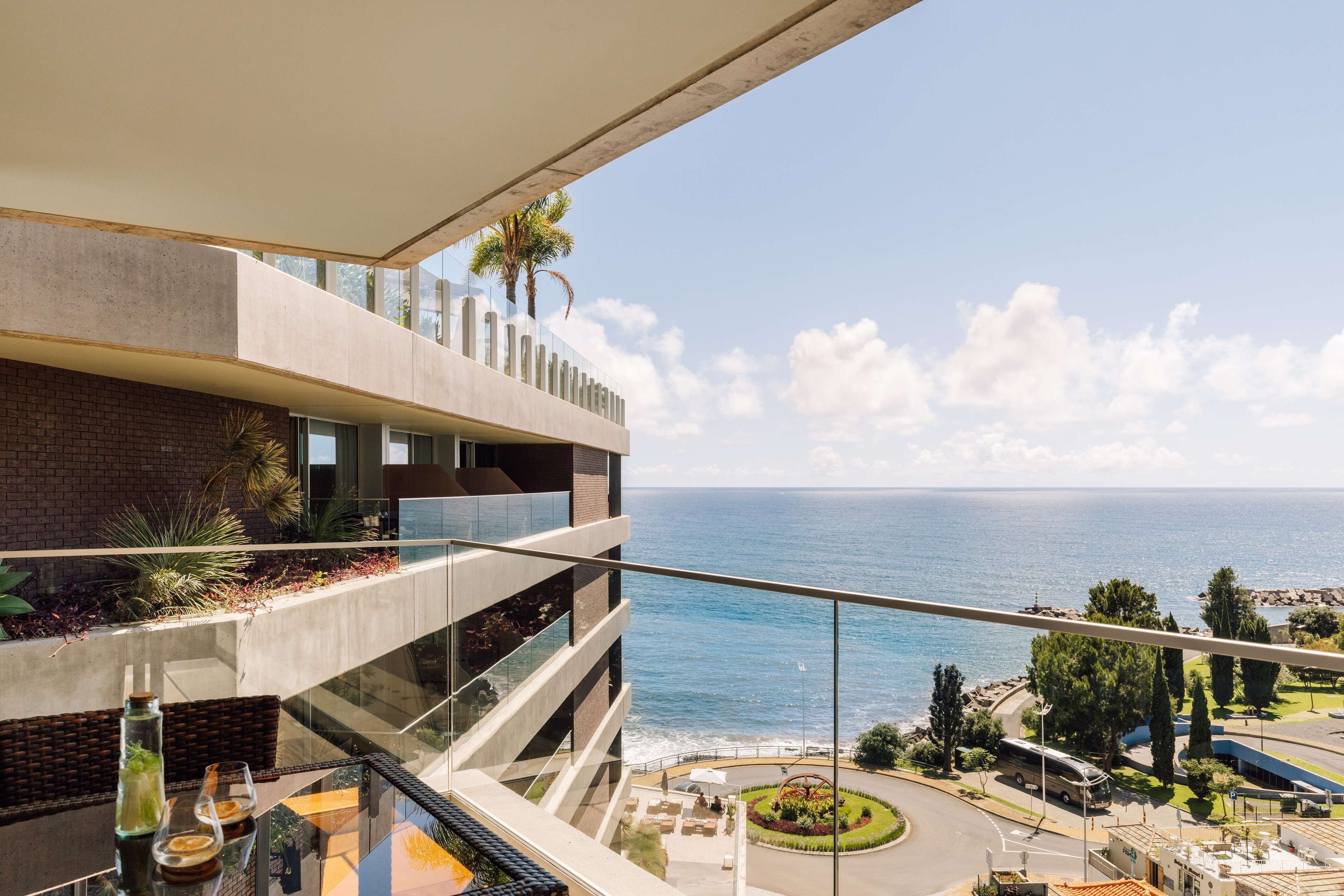 Ein modernes Gebäude mit einem Glasbalkon mit Blick auf das Meer.