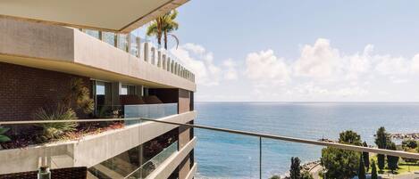 Un edificio moderno con balcón de cristal con vistas al mar.