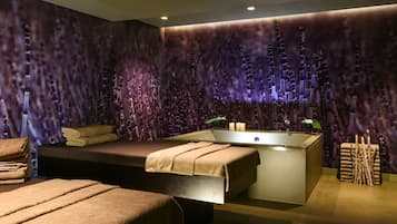 Une salle de spa moderne dotée d’une grande baignoire, d’une table de massage et d’un mur orné de décorations verticales évoquant le bambou.