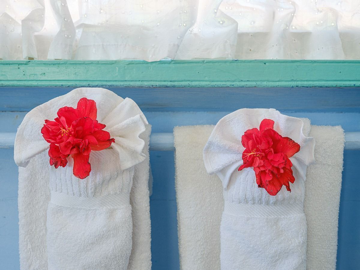 Zwei weiße Handtücher mit roten Blumen an einer blauen und weißen Wand.