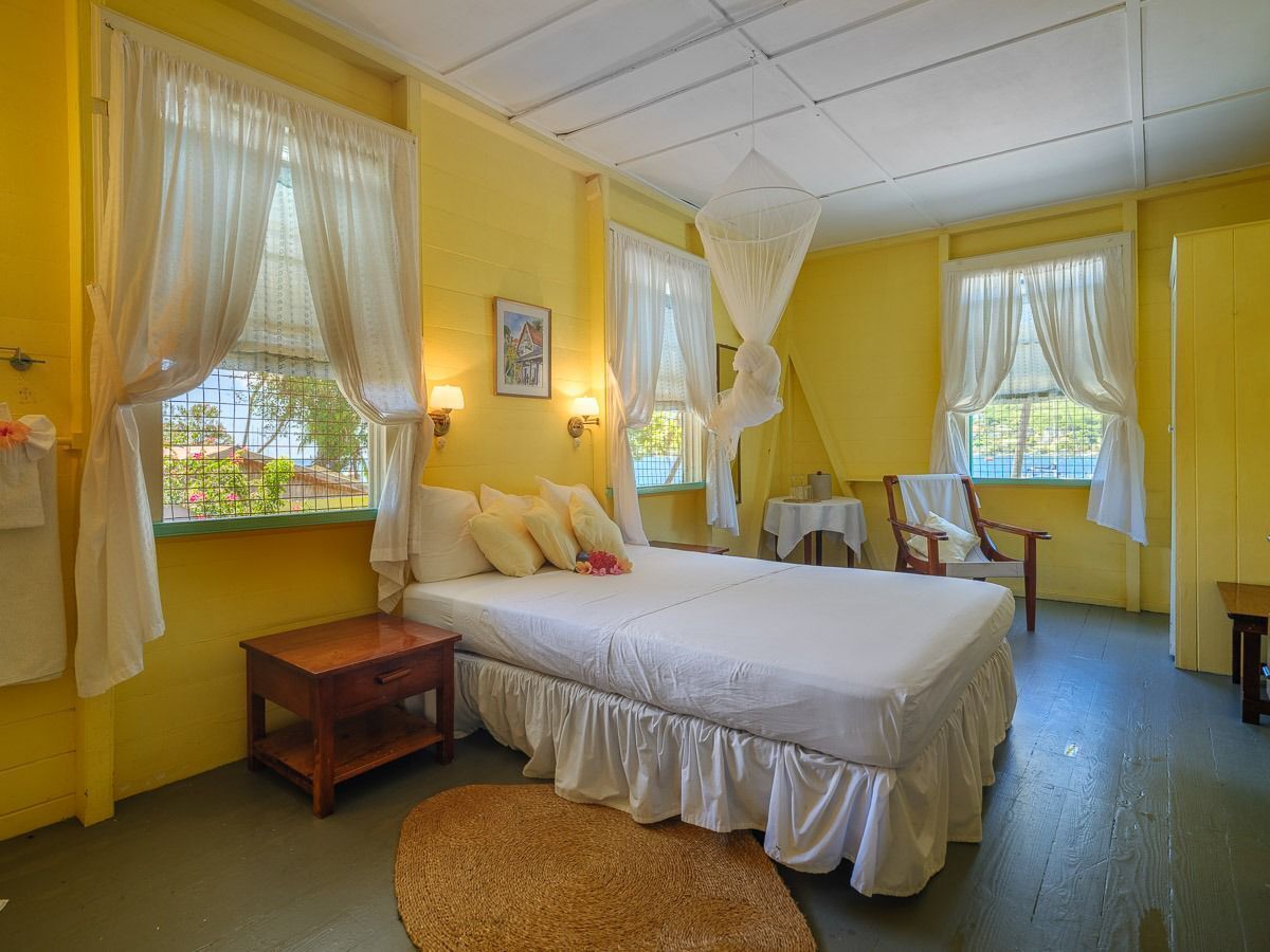Un dormitorio con cama, mesitas de noche, una silla y una ventana con cortinas.