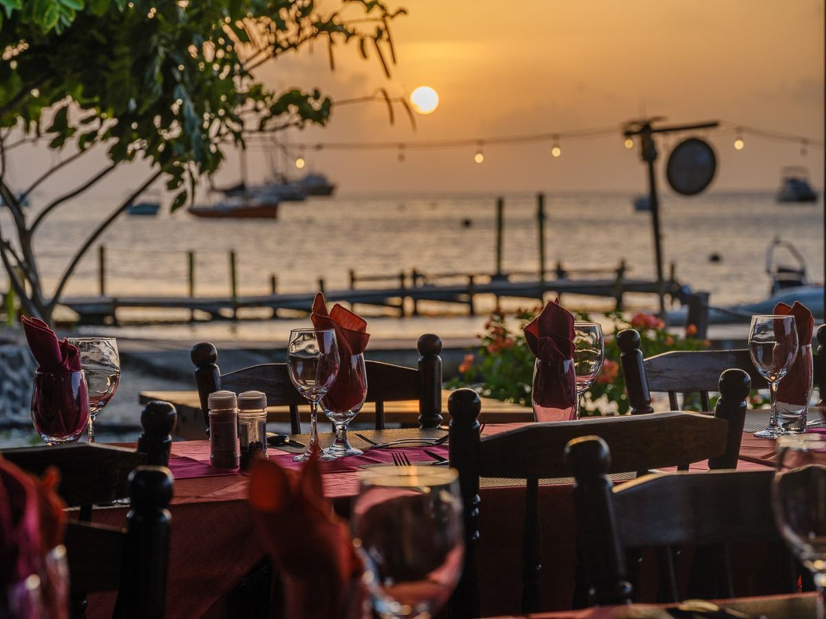 Een gedekte tafel met uitzicht op het water bij zonsondergang.