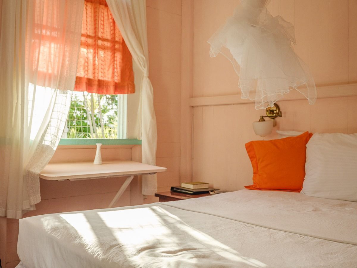 Un dormitorio con una cama, una mesita de noche, una ventana con cortinas y una planta en maceta.