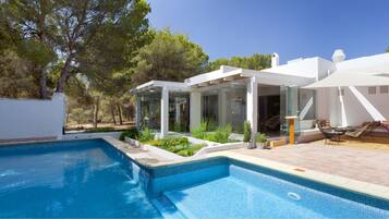 Una piscina al aire libre, sombrillas, tumbonas