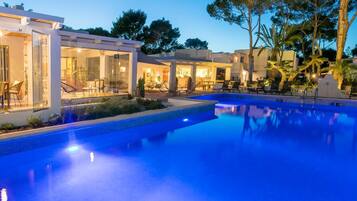 Un área de piscina moderna con estructuras de vidrio y mobiliario exterior.