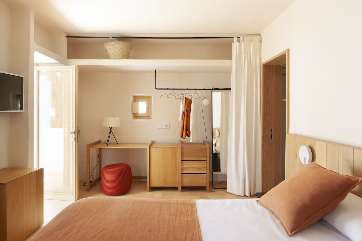 Quarto de hotel moderno com uma cama, uma escrivaninha, uma cadeira e um guarda-roupa.