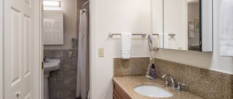 A bathroom with a sink, mirror, towel rack, and shower.