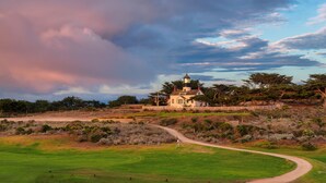 A lighthouse on a grassy hill with a clear path leading to it.