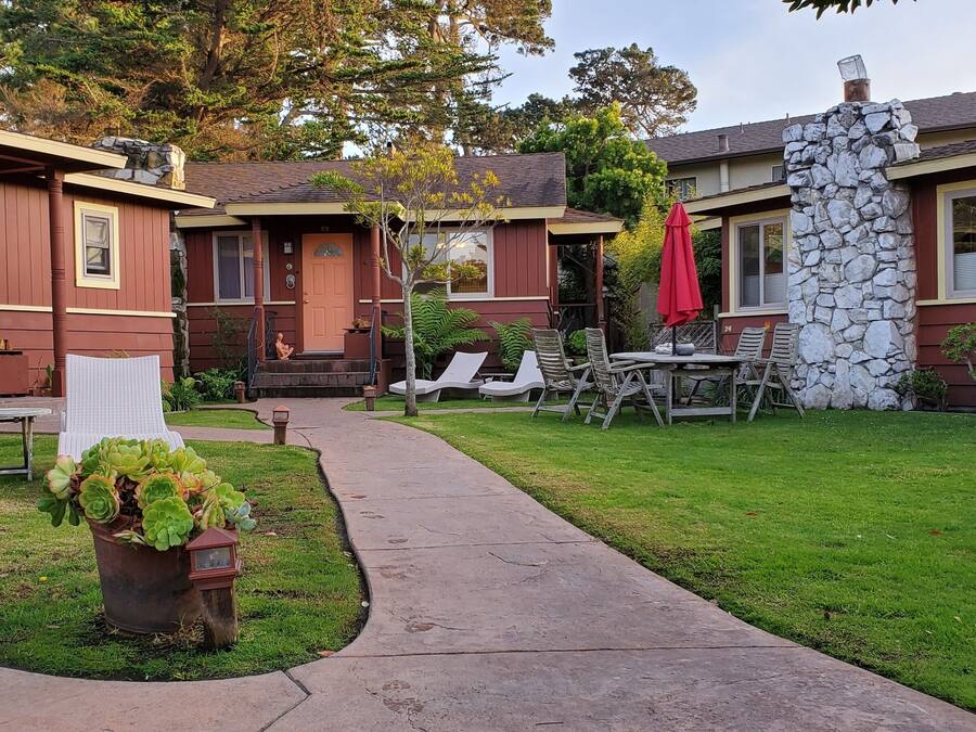 A two-story house with a stone wall, a blue door, and a patio with outdoor furniture.