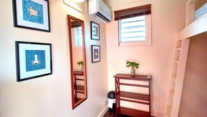 A narrow hallway with wooden flooring, a small table with a plant, and framed artwork on the walls. - Waterside Inn (Vieques)
