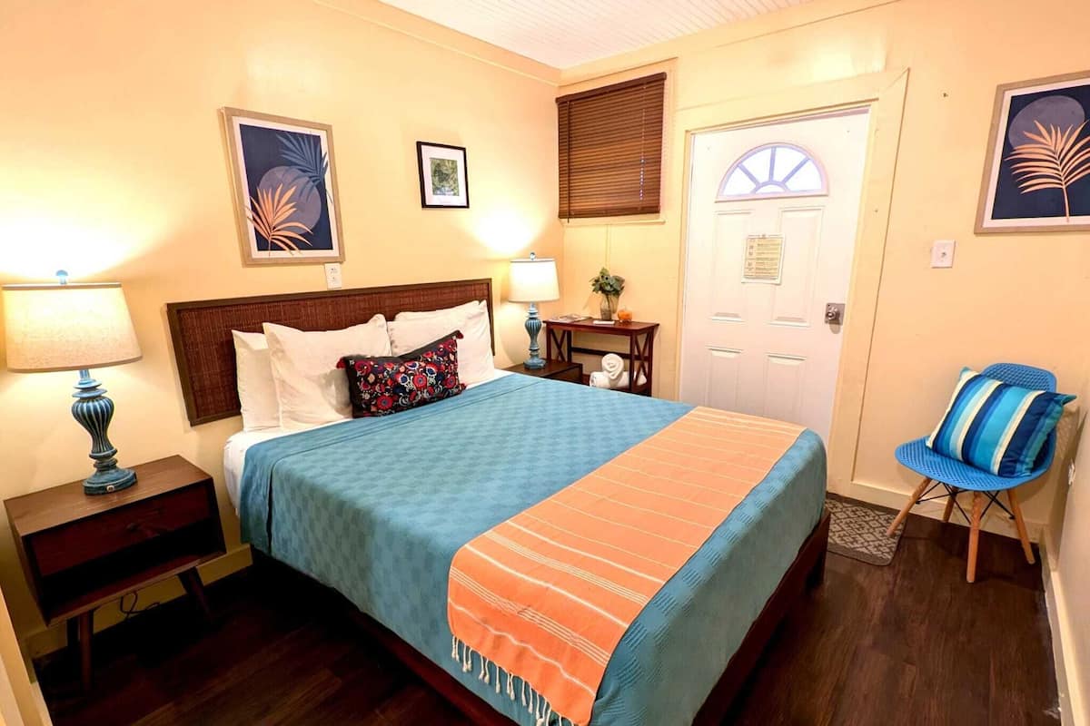 A bedroom with a bed, bedside tables, a chair, and artwork on the walls.