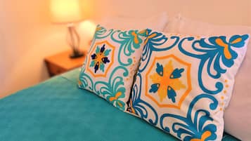 Un lit avec une couette et des oreillers décoratifs de couleur turquoise, ornés de motifs géométriques.