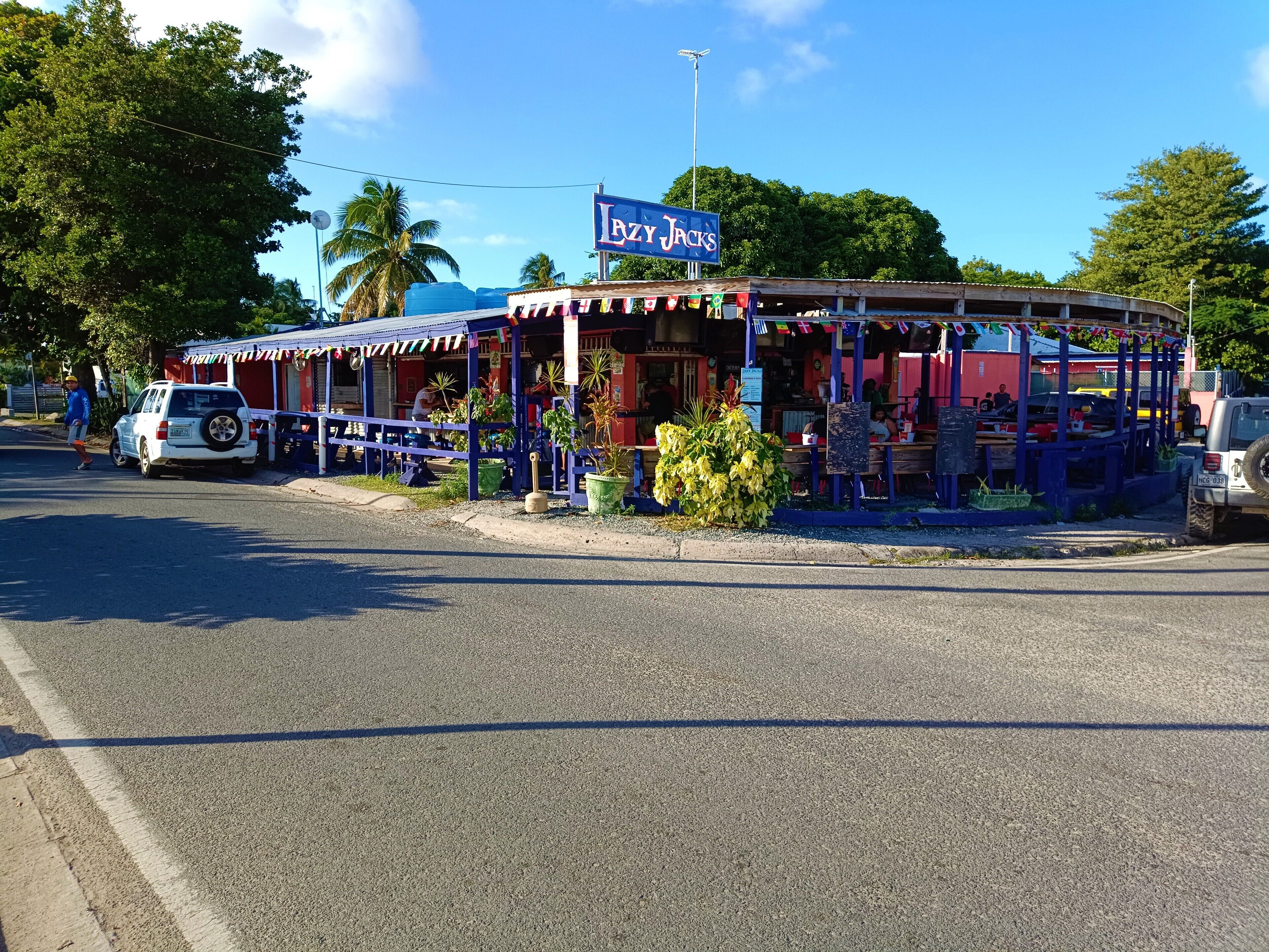 A building with a sign reading "LZY JACKS" and a covered outdoor seating area with tables and chairs.